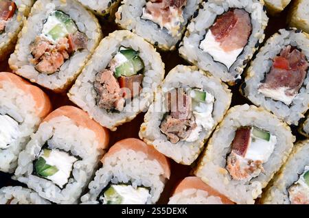 Nahaufnahme von vielen Sushi-Brötchen mit verschiedenen Füllungen. Makroaufnahme von gekochtem klassischem japanischem Essen. Hintergrundbild Stockfoto