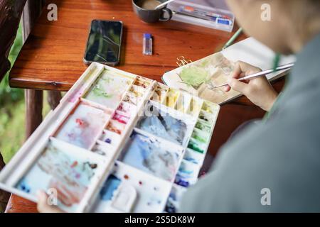 Student im Kunststudio. Hand haltender Künstler Pinsel mischen FarbÖlgemälde auf Palette Kunst Kreativität und Menschen Konzept. Stockfoto