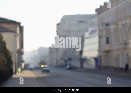 Die verschwommene Landschaft der Stadtstraßen mit fahrenden Autos und Straßenbahnen an einem nebeligen Morgen. Künstlerische Rezeption eines verschwommenen Landschaftsfotos mit Bokeh Stockfoto