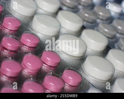Hintergrund mit zufälligen farbigen rosa, grauen und weißen Pillen in Makro. Farbige runde Pillen Stockfoto
