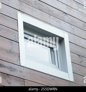 Kunststoff-PVC-Fenster in moderner Passivholzfassadenwand. PVC-Fenster sind die größte Energieeffizienz im Haus. Kunststoff-PVC-Fenster neu Stockfoto