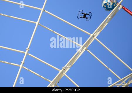Drohne mit Fotokamera startet vom Land und fliegt für Fotos vor dem Riesenrad. Die Drohne startet vom Land und fliegt, um Fotos zu machen Stockfoto