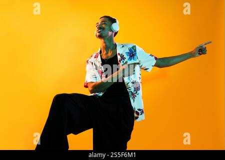Afrikanischer Mann junger Porträt im Studio auf bunter Hintergrund - cooler schwarzer junger Mann mit stilvoller Kleidung posiert, kreative farbige Beleuchtung Stockfoto