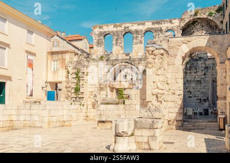 Alte Steinruinen mit Bögen und Säulen auf einem europäischen Stadtplatz unter einem klaren blauen Himmel, römische Straße mit silbernem Tor, Split, Kroatien Stockfoto