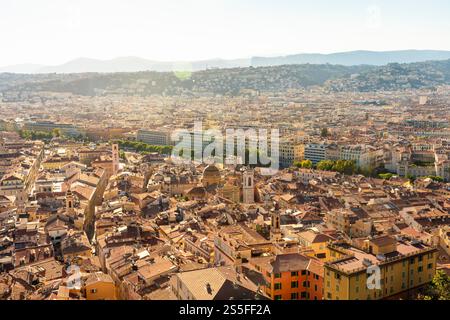 Aus der Vogelperspektive auf eine weitläufige Stadtlandschaft, die sich im goldenen Licht der Sonne mit klarem Himmel und dichten Häusern in Nizza, Frankreich, sonnt Stockfoto