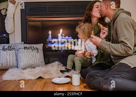 Familie genießt Kekse am Kamin mit Weihnachtsdekoration in einem gemütlichen Ambiente, Ohio, USA Stockfoto