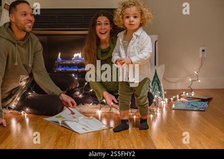 Eine fröhliche Familie liest gern am gemütlichen Kamin, mit Lichterketten für ein warmes Ambiente, Ohio, USA Stockfoto