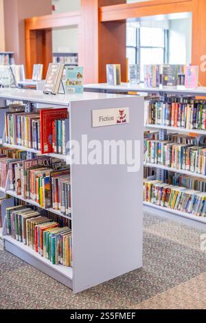 Fiktionale Sektion in einer Bibliothek mit Bücherregalen voller Bücher und einem beschrifteten Stand im Vordergrund. Cleveland Public Library, Ohio, USA Stockfoto