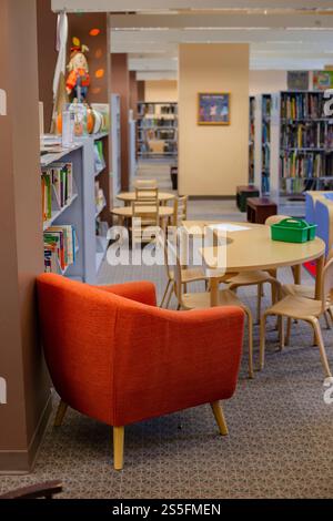 Stühle um einen Tisch in einer Bibliothek mit Bücherregalen und Kinderspielzeug und -Bücher im Hintergrund. Cleveland, Ohio, USA Stockfoto