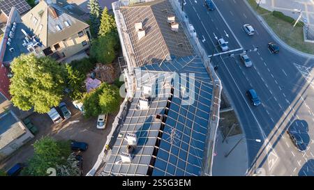 Aus der Vogelperspektive auf eine Baustelle mit einem Gebäude, das gerade renoviert wird, mit Gerüsten und einem teilweise fertiggestellten Dach. In der Nähe, eine befahrene Straße mit se Stockfoto