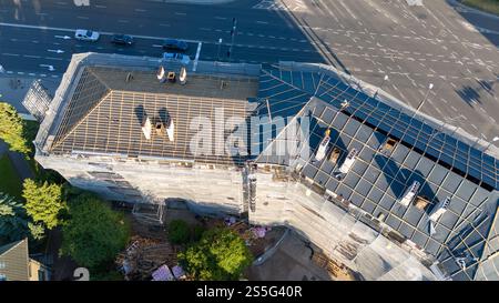 Aus der Vogelperspektive eines Gebäudes im Bau mit Gerüsten und teilweise fertiggestelltem Dach. Stockfoto