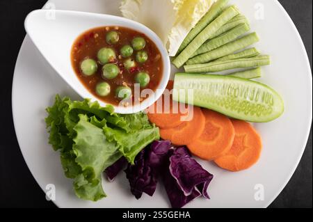 Garnelenpaste-Sauce in einer Schüssel auf dem weißen Teller mit Gurke, Yard Langhaar Bohnen, thai Auberginen, gebratenem Weißkohl, Karotten und Salat. Stockfoto