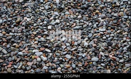Eine Nahaufnahme farbenfroher, glatter Kieselsteine und Steine mit natürlichen Texturen und Erdtönen. Stockfoto
