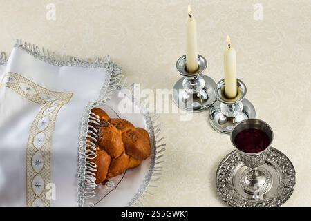Einstellung Sabbath-Tisch. Eleganter Sabbattisch mit geflochtenem Brot, Kerzen und Weinbecher. Stockfoto