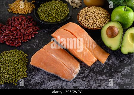 Leguminosen, Obst und Lachs auf einem schwarzen Zementboden. Stockfoto
