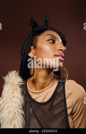 Die schöne junge Frau zeigt einen einzigartigen Stil mit geflochtenen Haaren und auffälligem Schmuck während der Pose. Stockfoto