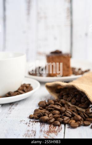 Kaffeebohnen in Hanfsäcken auf einem weißen Holztisch. Selektiver Fokus. Stockfoto