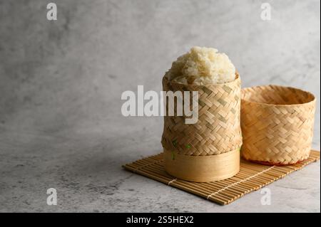 Thailändischer Kleberreis in einem gewebten Bambuskorb auf einer Holzplatte. Selektiver Fokus. Stockfoto
