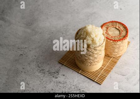 Thailändischer Kleberreis in einem gewebten Bambuskorb auf einer Holzplatte. Selektiver Fokus. Stockfoto
