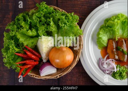 Top View Zutat Kraut zum Kochen von Salat in einem Korb und Sardine mit Tomatensauce in einer weißen Schale auf Holztisch, Stockfoto