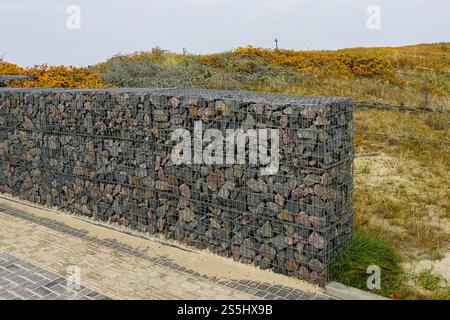 Moderne Entwicklung der Strandpark-Umwelteinrichtungen, Gabionenzaun-Wand aus Stahlgitter gefüllt mit Steinen, die die Bewegung von Dünensand einschränken Stockfoto