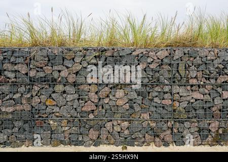 Moderne Entwicklung der Strandpark-Umwelteinrichtungen, Gabionenzaun-Wand aus Stahlgitter gefüllt mit Steinen, die die Bewegung von Dünensand einschränken Stockfoto