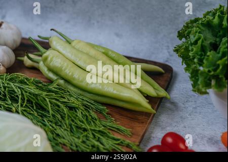 Cha-om, süßer Pfeffer und Knoblauch auf einem hölzernen Schneidebrett. Stockfoto