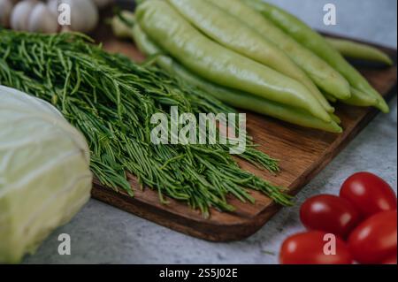 Cha-om, süßer Pfeffer und Knoblauch auf einem hölzernen Schneidebrett. Stockfoto