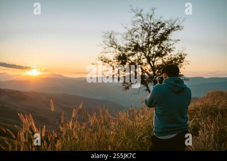 Wanderabenteuer allein für Touristen. Junger Mann, der auf einer Klippe in den Sommerbergen mit Sonnenuntergang steht, genießen Sie den Blick auf die Natur Klippe Berg. Stockfoto