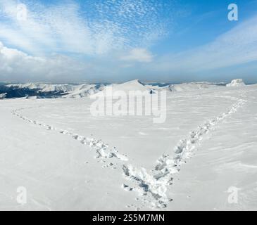 Menschlichen Fußabdruck bilden die Herzform auf schneebedeckten Berg-Plateau und Bergketten hinter. Stockfoto