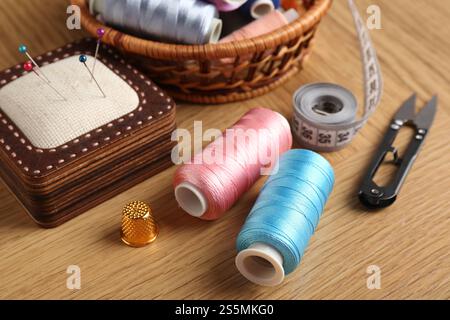Nähgarne, Schere, Kissen und Kausche auf Holztisch, Großaufnahme Stockfoto