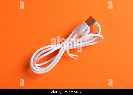 USB-Ladekabel auf orangefarbenem Hintergrund, Draufsicht Stockfoto