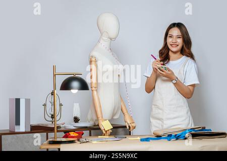 Porträt eines jungen hübschen weiblichen Modedesigners stilvolles Lächeln während der Arbeit im Modestudio, Schneiderinnen messen mit Messungen Stockfoto
