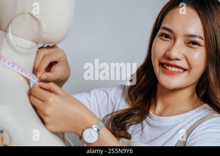 Porträt eines jungen hübschen weiblichen Modedesigners stilvolles Lächeln während der Arbeit im Modestudio, Schneiderinnen messen mit Messungen Stockfoto