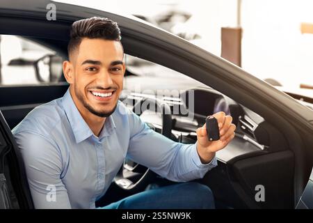 Hübscher arabischer Mann, der im Auto sitzt und den Schlüssel hält Stockfoto