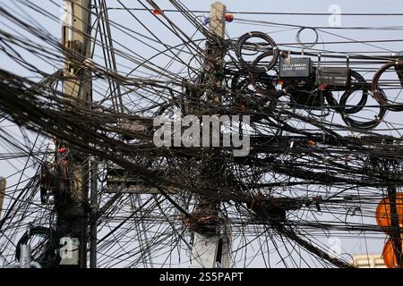 Kommunikations- und Stromübertragungskabel sind an einem Straßenmast im Zentrum von Bangkok, Thailand, befestigt. Stockfoto