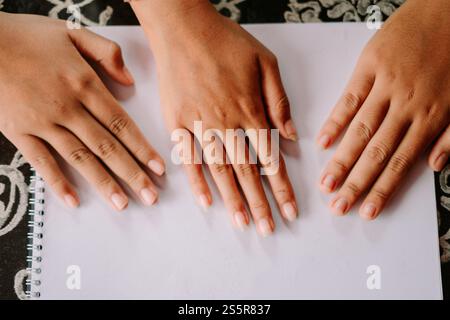 Drei Hände auf einer leeren weißen Seite, bereit zum Schreiben oder Zeichnen. Stockfoto
