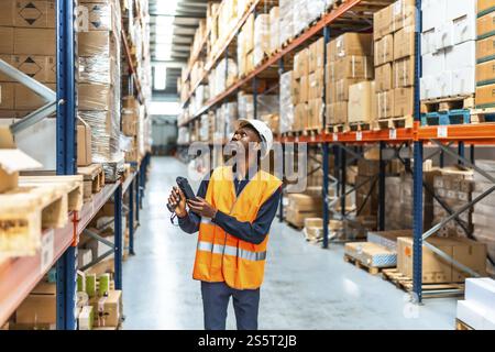 Afrikanischer Arbeiter, der Pakete im Lagerraum eines Verteilerlagers scannt Stockfoto