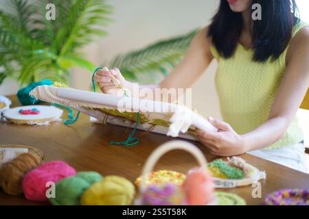 Stanznadel. Asiatische Frau, die handgemachtes Hobby-Stricken in der Atelierwerkstatt herstellt. Designer-Arbeitsplatz Handgefertigtes Bastelprojekt DIY Stickkonzept Stockfoto