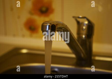 Wasser läuft vom Wasserhahn herunter. Wasserhahn im Spülbecken Stockfoto