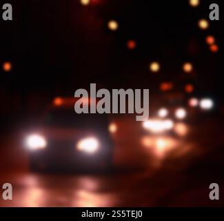 Unscharfe Verkehrslichter auf einer nassen regnerischen Stadtstraße bei Nacht - Pendeln zur Rush Hour Konzept abstraktes Bokeh von der Verkehrsbeleuchtung auf dem Verkehr Stockfoto