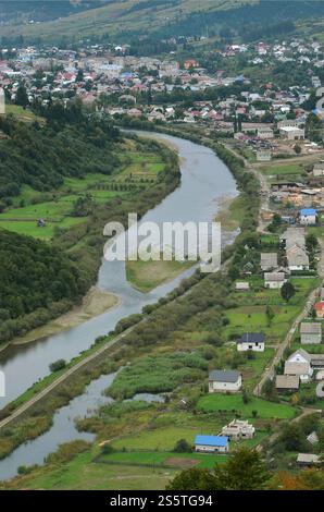 Eine wunderschöne Aussicht auf das Dorf Mezhgorye, Karpaten Region. Eine Menge von Wohngebäuden durch hohe Wald Berge und lange Fluss umgeben Stockfoto