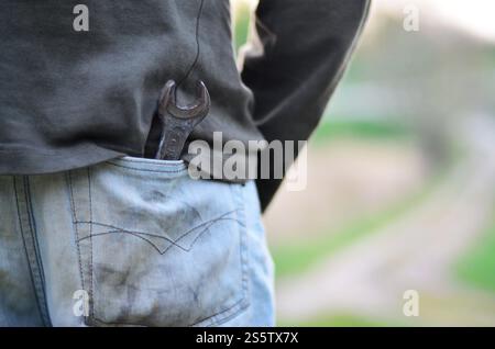 Schlüssel in die Jeans Tasche ein Mechaniker im Freien. Das Konzept für die Reparatur eines Autos oder Anlagen mit seinen eigenen Händen in der Luft Stockfoto