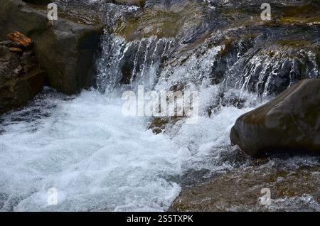 Nahaufnahme von einem kleinen wilden Wasserfall in Form von kurzen Ströme von Wasser zwischen Berg Steine Stockfoto