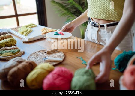 Stanznadel. Asiatische Frau, die handgemachtes Hobby-Stricken in der Atelierwerkstatt herstellt. Designer-Arbeitsplatz Handgefertigtes Bastelprojekt DIY Stickkonzept Stockfoto