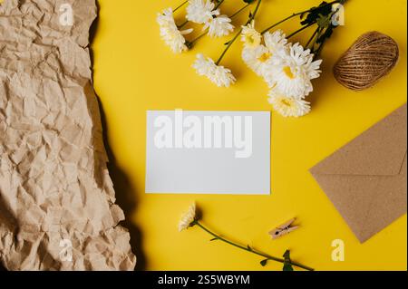 Leere Karte mit Umschlag und Blume ist auf gelbem Hintergrund platziert Stockfoto