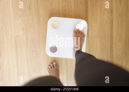 Abnehmen. Fettdiät und Schuppenfüße stehen auf elektronischen Waagen zur Gewichtskontrolle. Messgerät in Kilogramm für Diät Stockfoto
