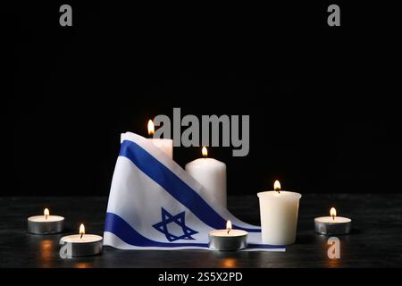 Brennende Kerzen und Flagge Israels auf dunklem Hintergrund. Holocaust-Gedenktag Stockfoto