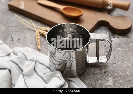 Metallmehl Siebbecher, Serviette und Küchenutensilien auf Grunge Hintergrund Stockfoto