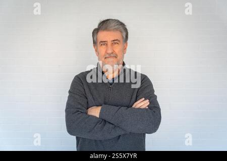 Weißer Seniorenmann mit Bart und überkreuzten Armen und Blick in die Kamera Stockfoto